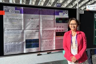 Dr Joanne Matsubara stands before her poster at AAIC